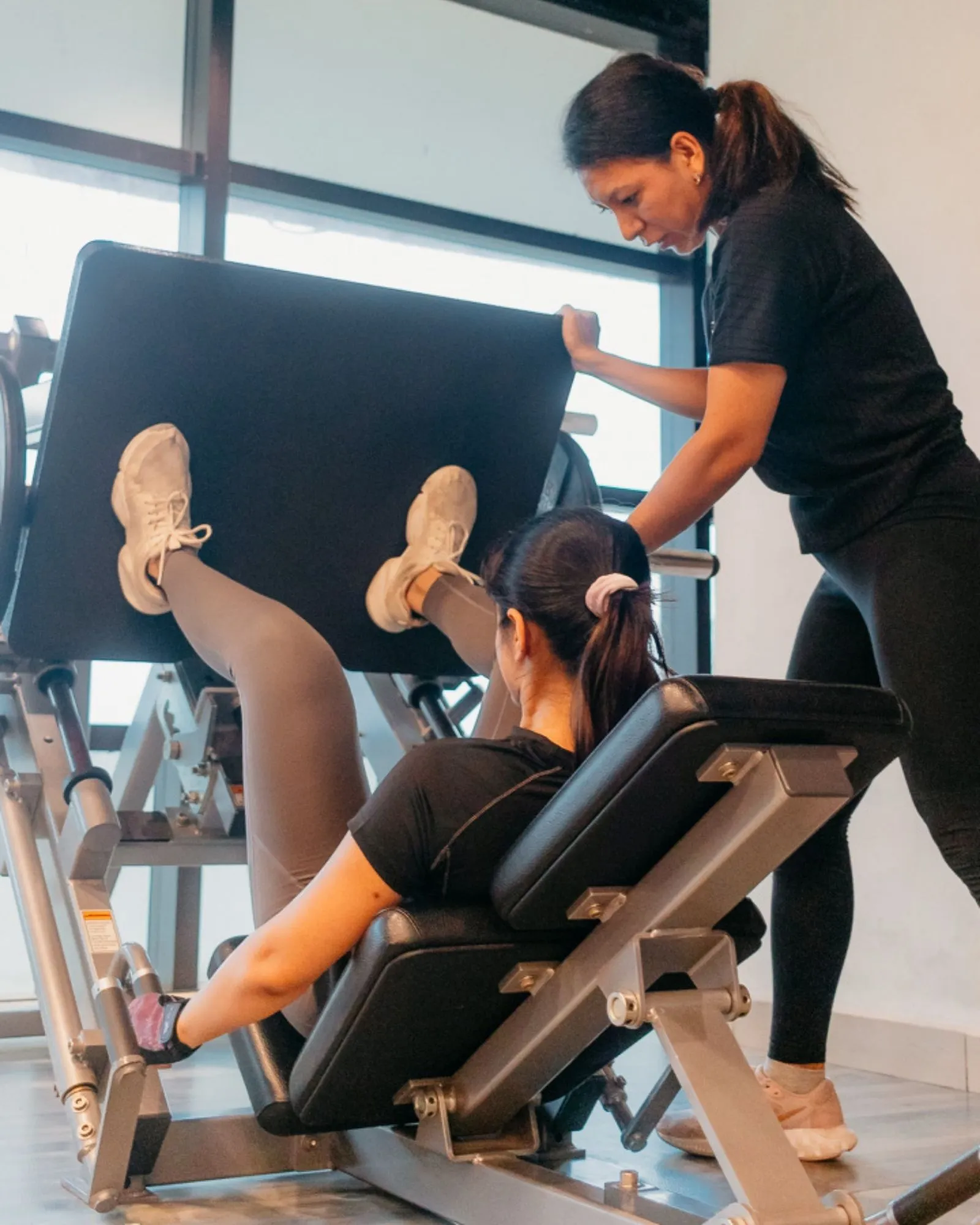 Coach guiding a client through a leg press set